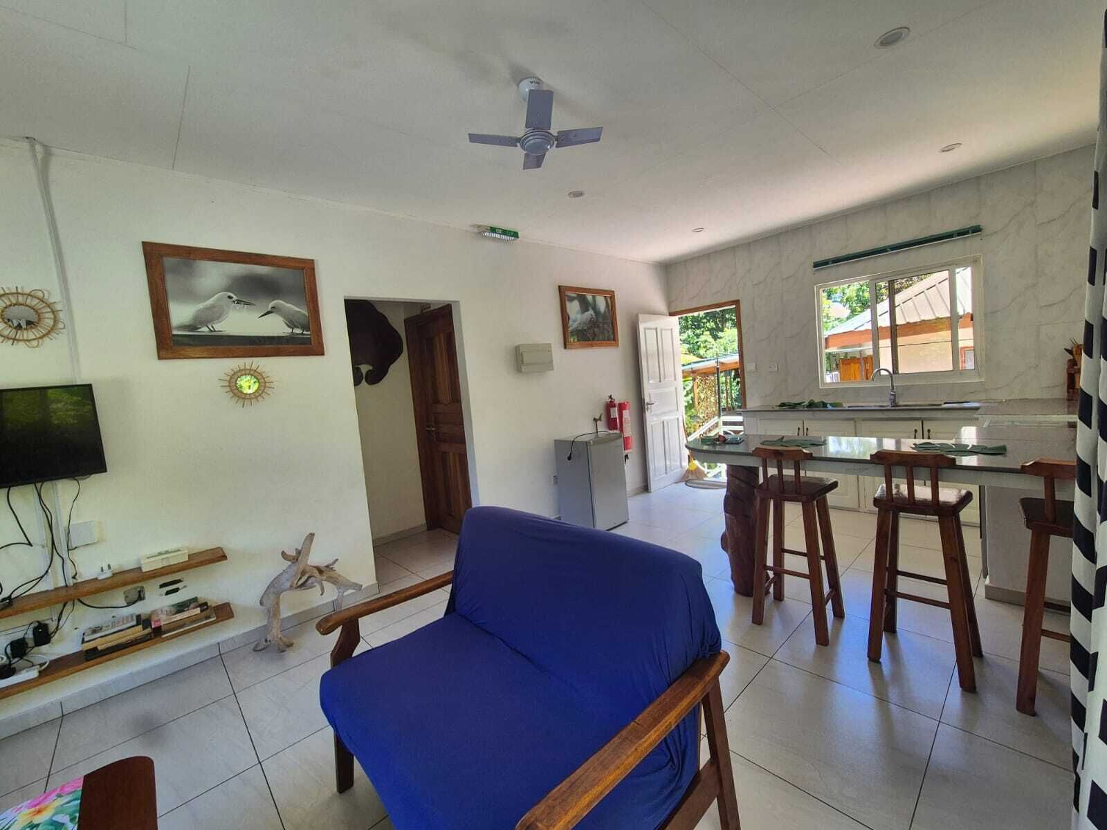 Una sala de estar con un sofá azul, un televisor y una pequeña estatua de perro.