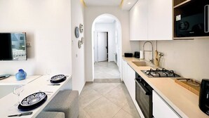 Eine moderne Küche mit Essbereich, einem an der Wand montierten Fernseher und Blick in den Wohnbereich.