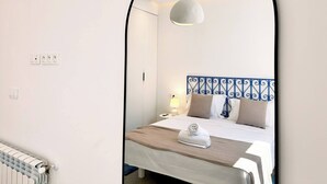 Ein Hotelzimmer mit einem Bett, einem Nachttisch, einer Lampe, einem Spiegel und einer Heizung.