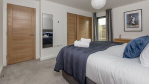 A bedroom with a bed, a wardrobe, a mirror, a nightstand, and a framed picture on the wall. - Designer Urban Apartment with City Terrace (Edinburgh)