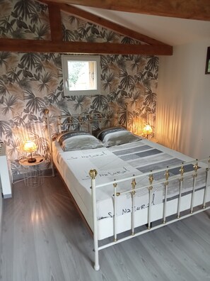 Un dormitorio con cama, mesita de noche, lámpara y ventana.