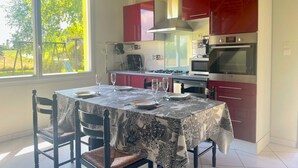 Cozinha moderna com armários vermelhos, mesa de jantar posta para quatro pessoas e uma janela grande com vista para o exterior.
