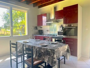 Una cocina moderna con armarios rojos, una mesa de comedor para cuatro personas y un ventanal con vistas al exterior.