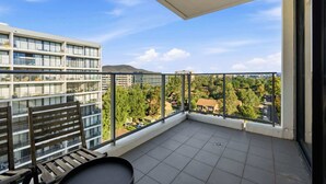 Un balcon offrant une vue sur les bâtiments et les arbres environnants.