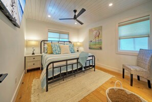 A bedroom with a bed, nightstand, chair, and a ceiling fan. - 2 Homes + Pools + Game Room + Sunset Views | Boujee Pelican & Tipsy Flipper (Port Aransas)