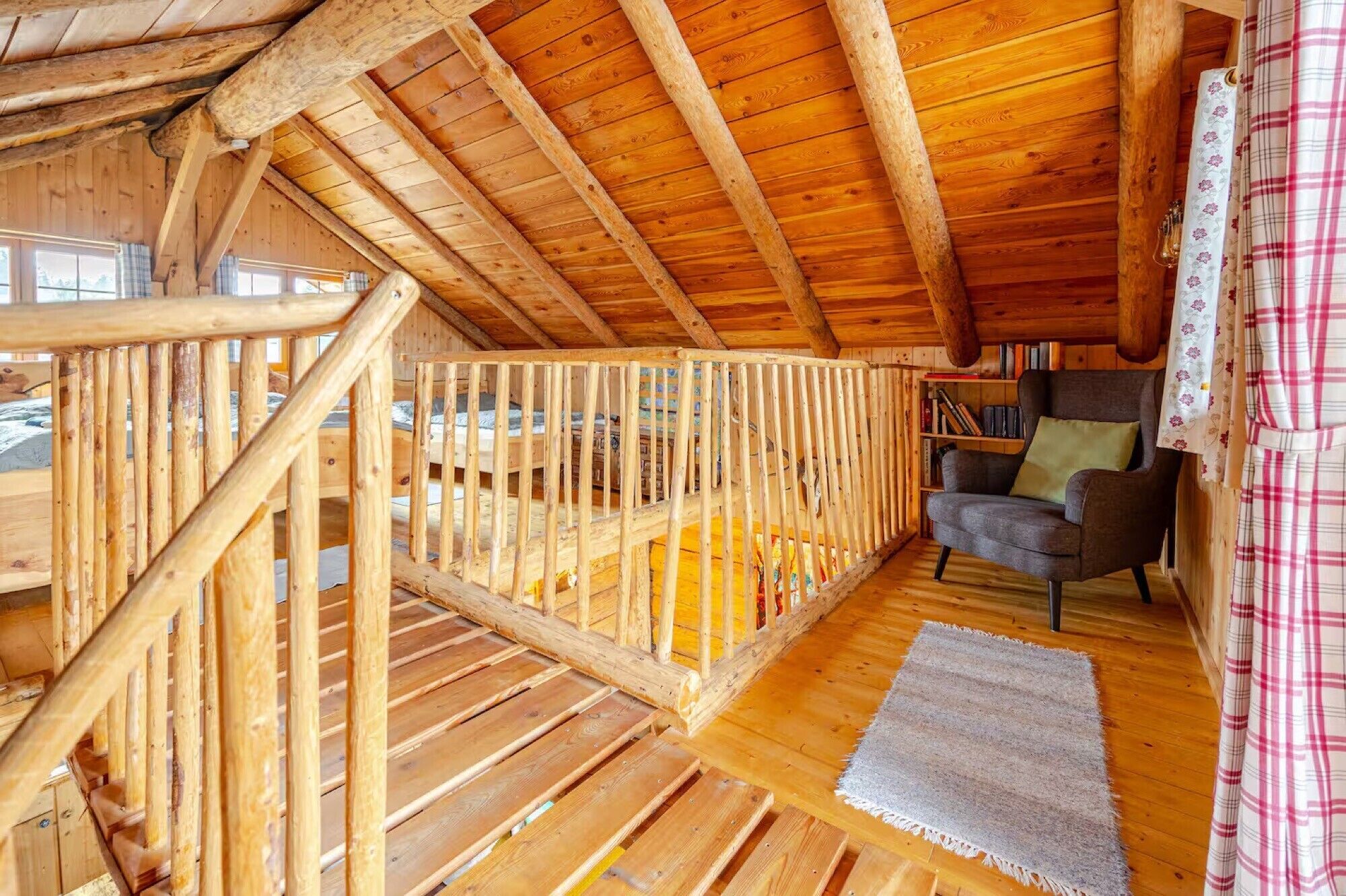 A wooden interior with a balcony, a chair, and a bookshelf.