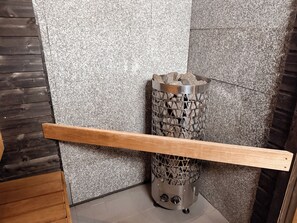 A corner of a room with a textured wall, a metal object with a grid pattern, and a wooden beam.