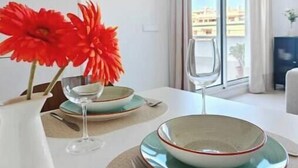 A dining table with plates, a glass, and a vase with flowers. - New apartment near the beach - medium term stays (ideal for couples) (Torre del Mar)