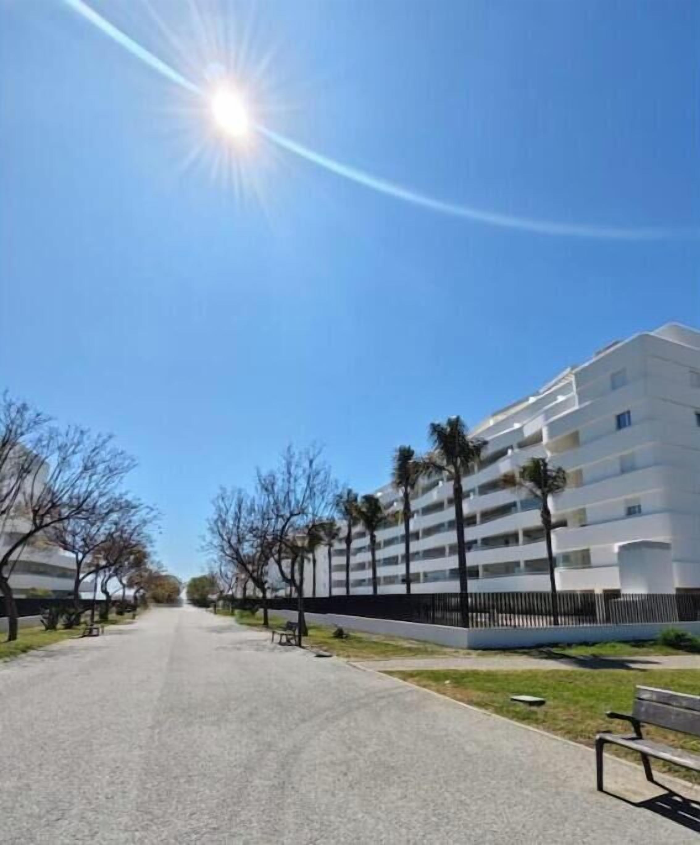 A clear sky, a paved pathway, and a multi-story building with balconies.