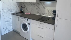 Eine kleine Küche mit Waschmaschine, Spüle und Mikrowelle.