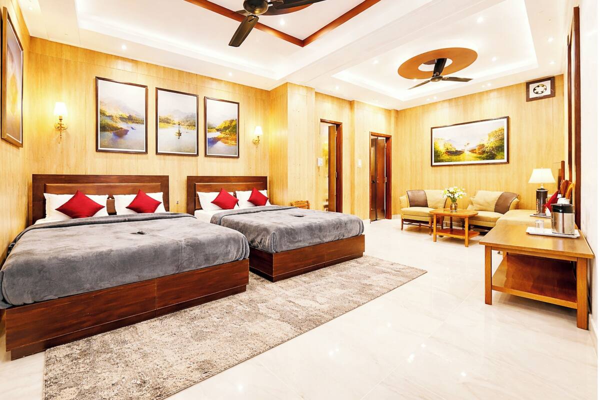 Habitación de hotel con dos camas, un sofá, una mesa de centro y un ventilador de techo.