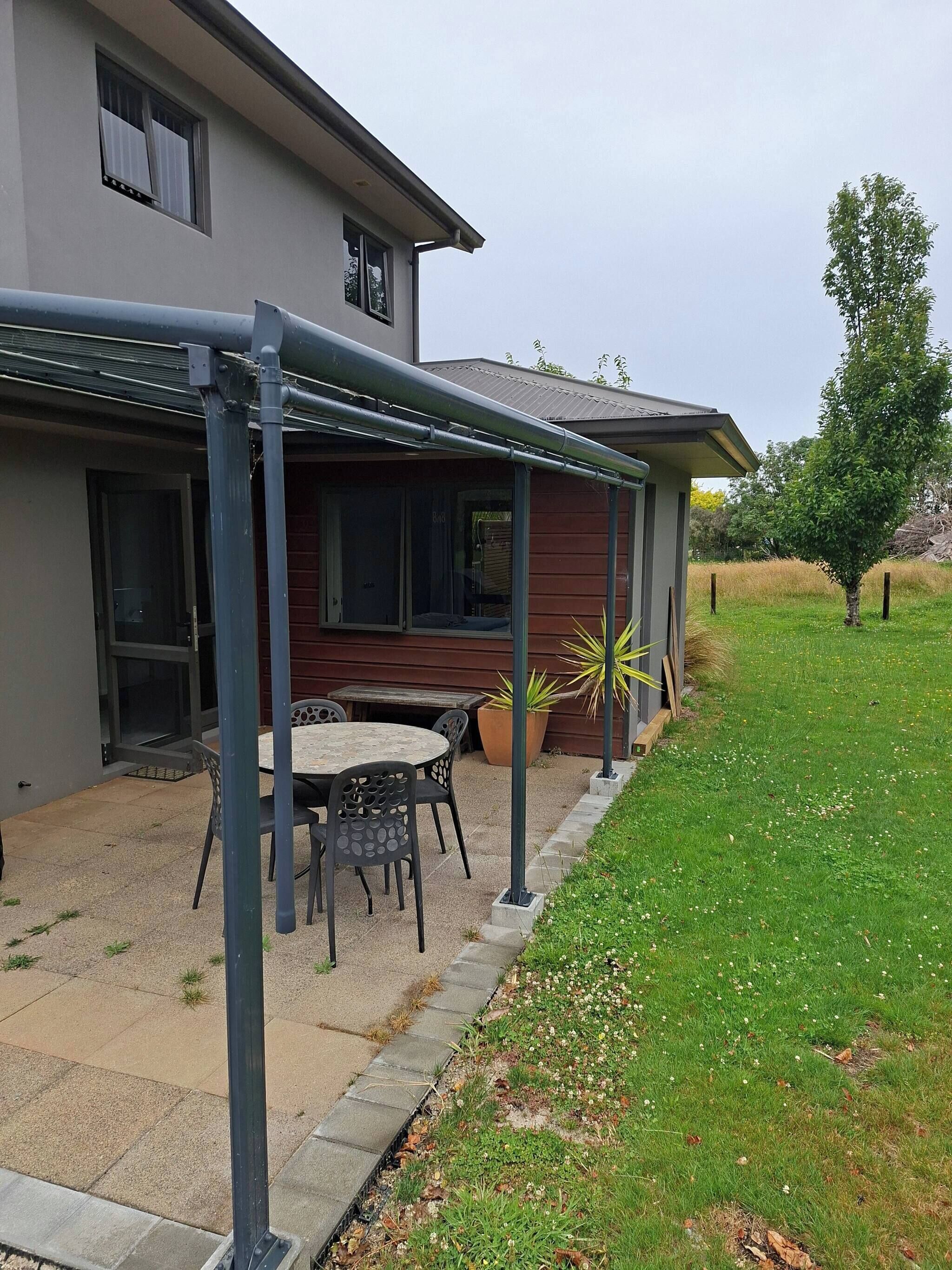 Une maison avec un patio couvert, une table à manger et des chaises.