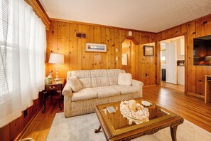 Ein Zimmer mit Holzwänden, einer Couch, einem Tisch mit Kerze und einem Fernseher.