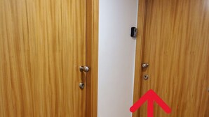 Ein Korridor mit Holztüren, einer Lampe und einem roten Pfeil, der nach oben zeigt.