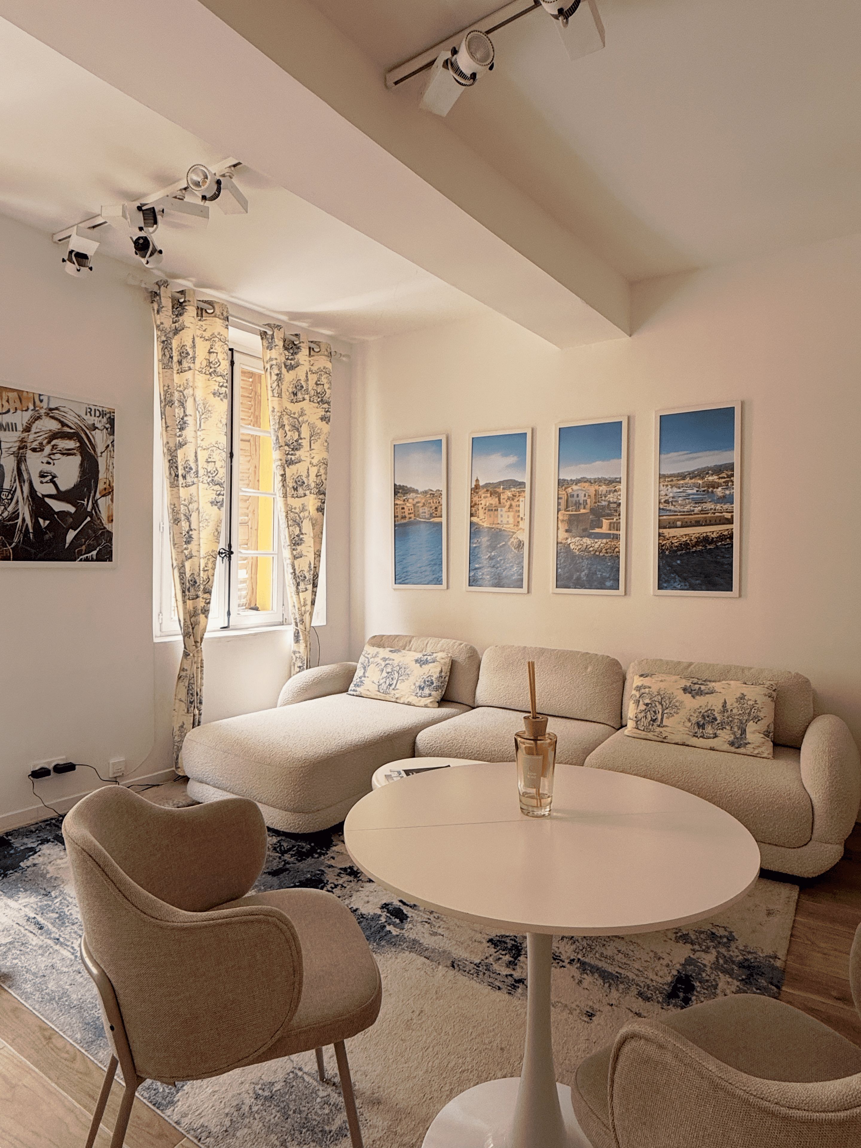 A cozy living room with a sofa, a round table, and a window with curtains.
