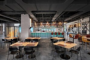 En modern restaurang med en bardel, bord och stolar som är placerade för att skapa en trevlig matplats.