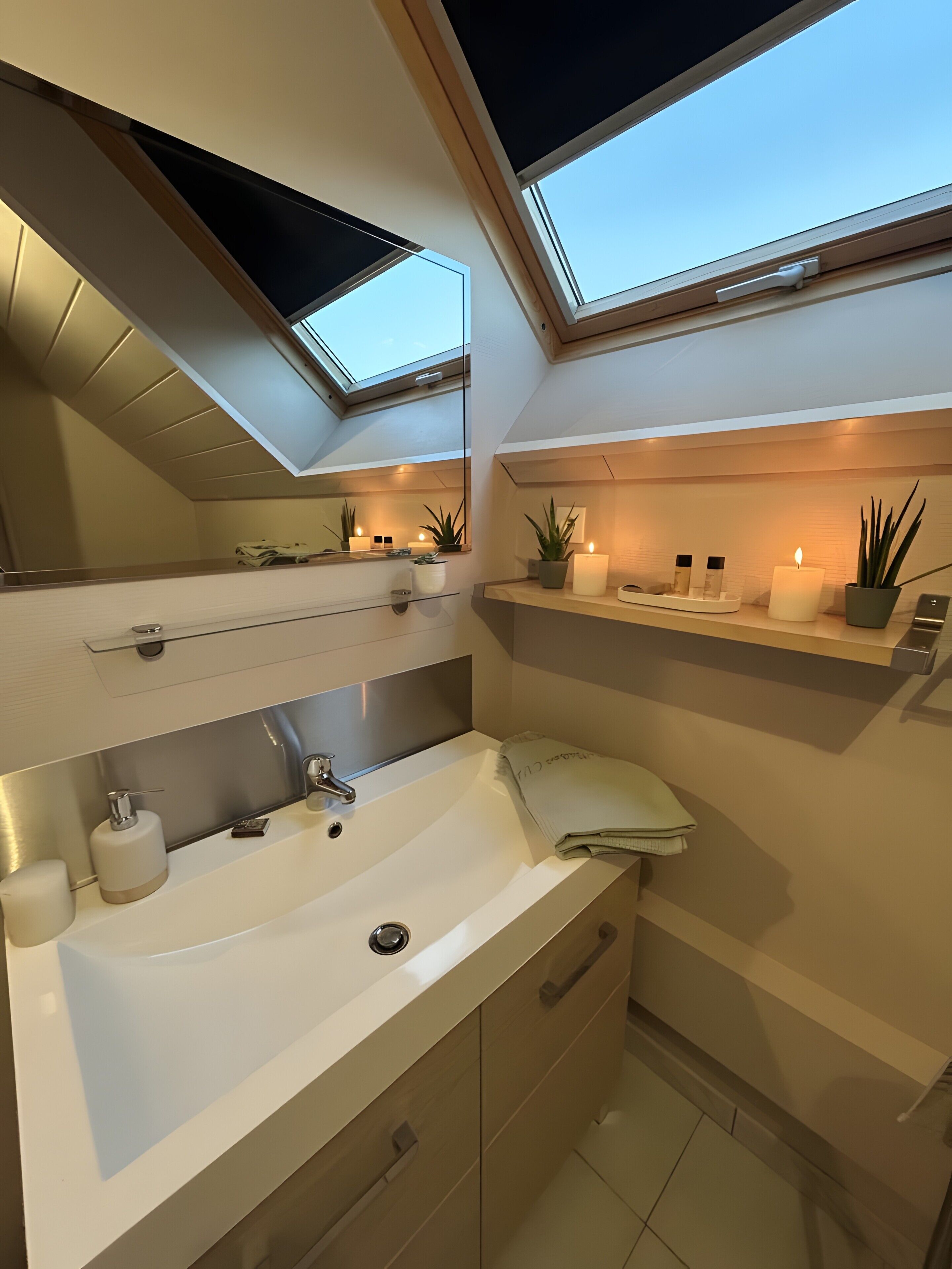 A modern bathroom with a skylight, a sink, a mirror, and a shelf with toiletries.