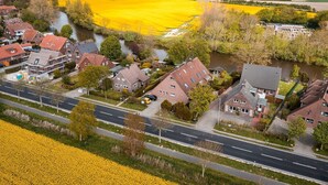 Un quartier résidentiel avec des maisons, une rivière et des champs de fleurs jaunes.