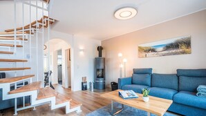 Un salon moderne avec un escalier, un canapé bleu, une table basse en bois et une cheminée.