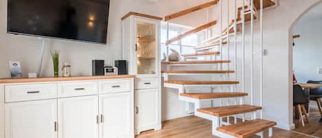 Une cuisine moderne avec des armoires blanches, un plan de travail en bois et un téléviseur encastré.