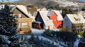 Een woonwijk met huizen, een besneeuwd landschap en een heldere lucht.
