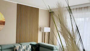 Een moderne woonkamer met een hoekbank, een houten salontafel, een lamp en een hoge plant.