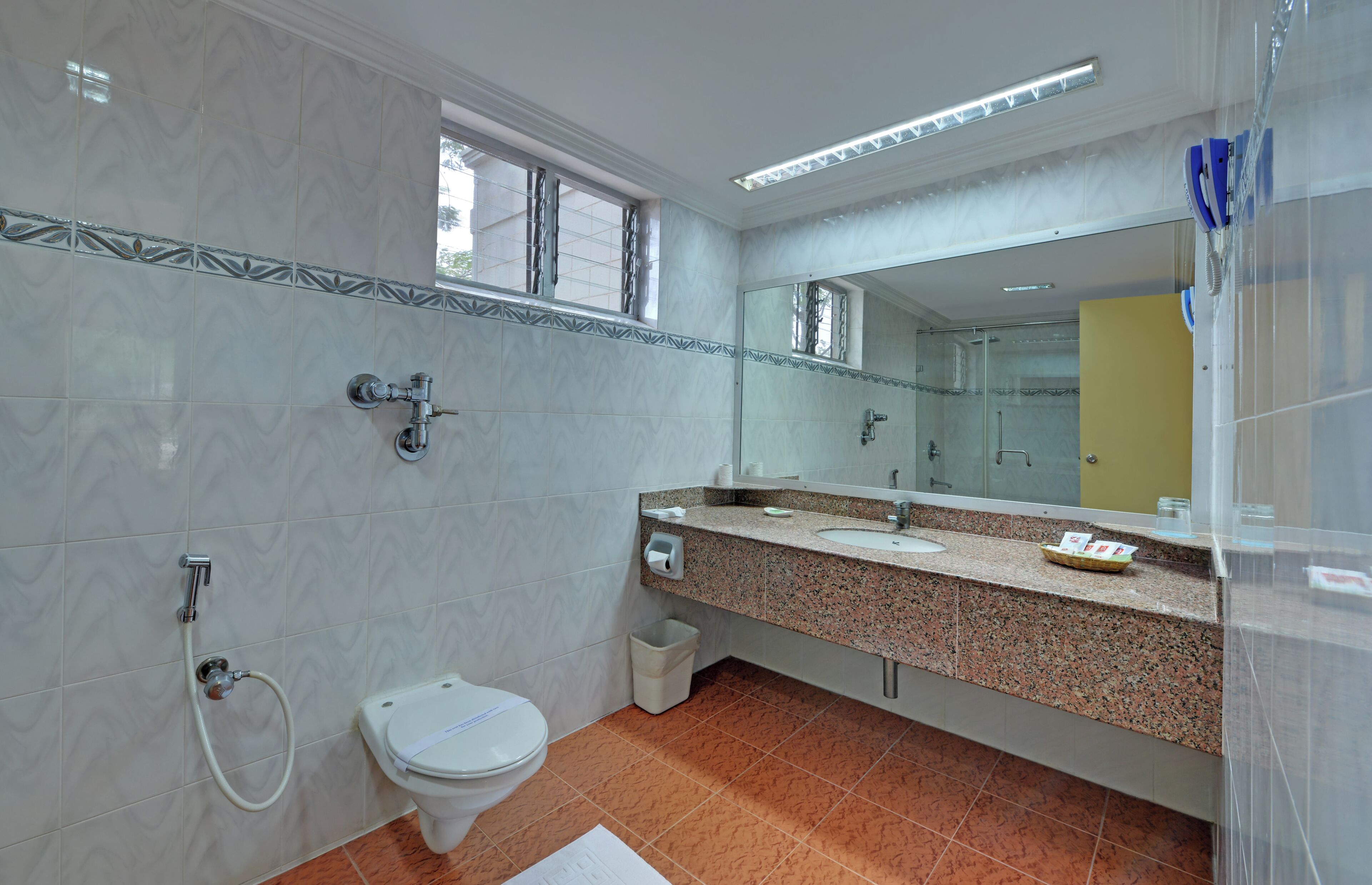 A bathroom with a toilet, sink, mirror, and shower.