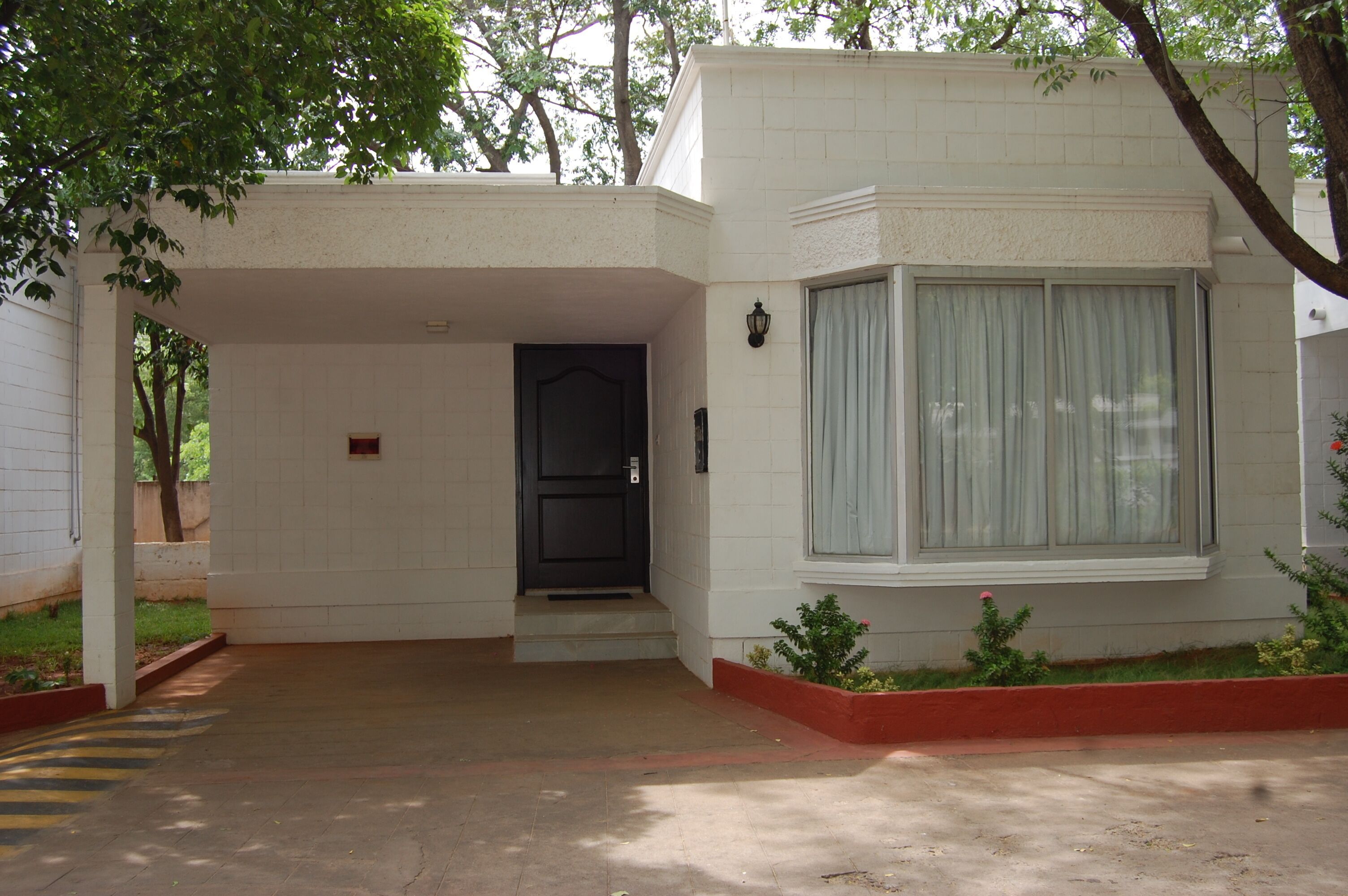 A building with a white exterior, a black door, and a window with a white curtain.