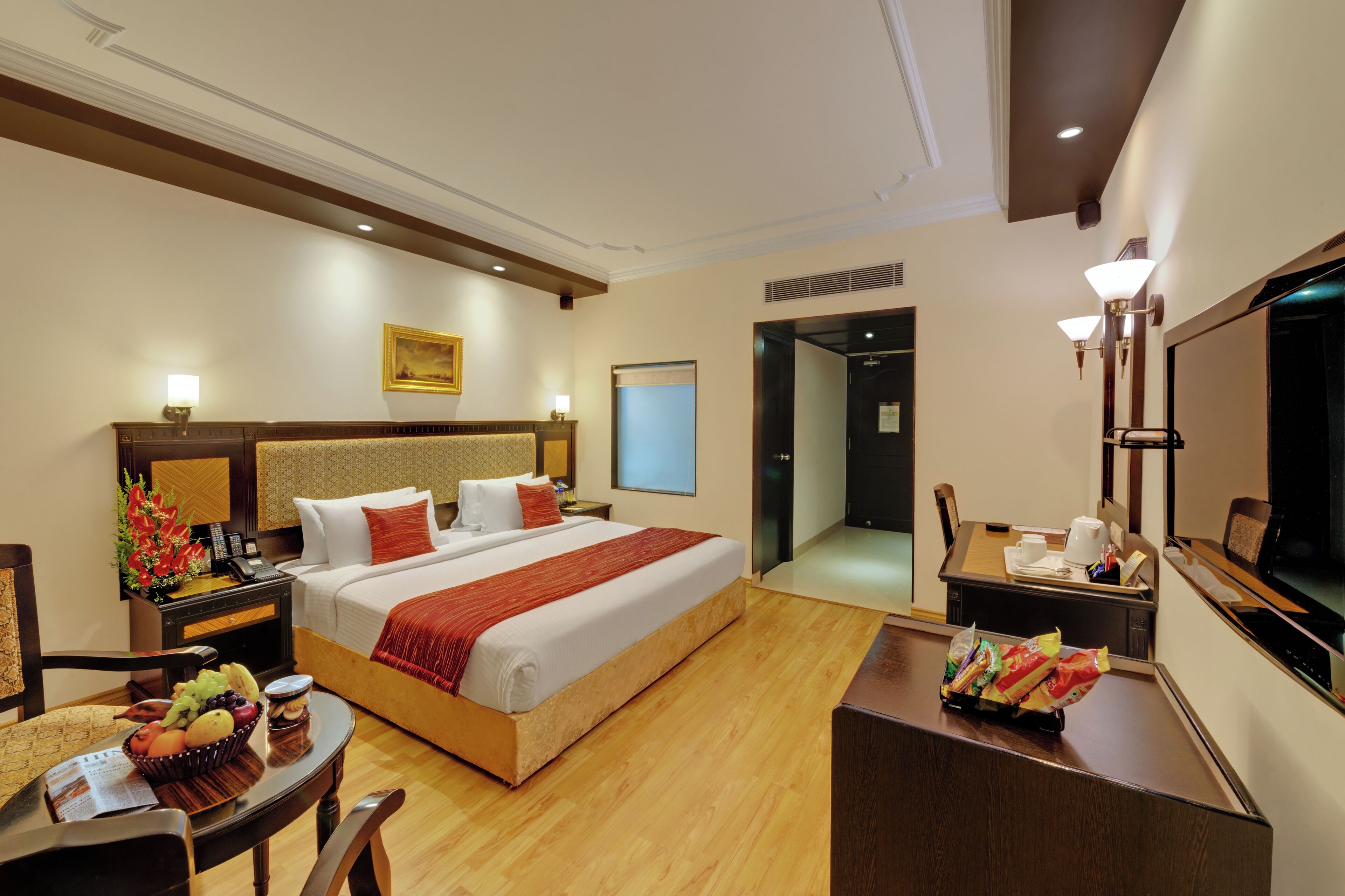 A hotel room with a bed, bedside tables, a desk, a chair, and a television.