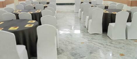 A conference room with round tables and white chairs, arranged in rows.