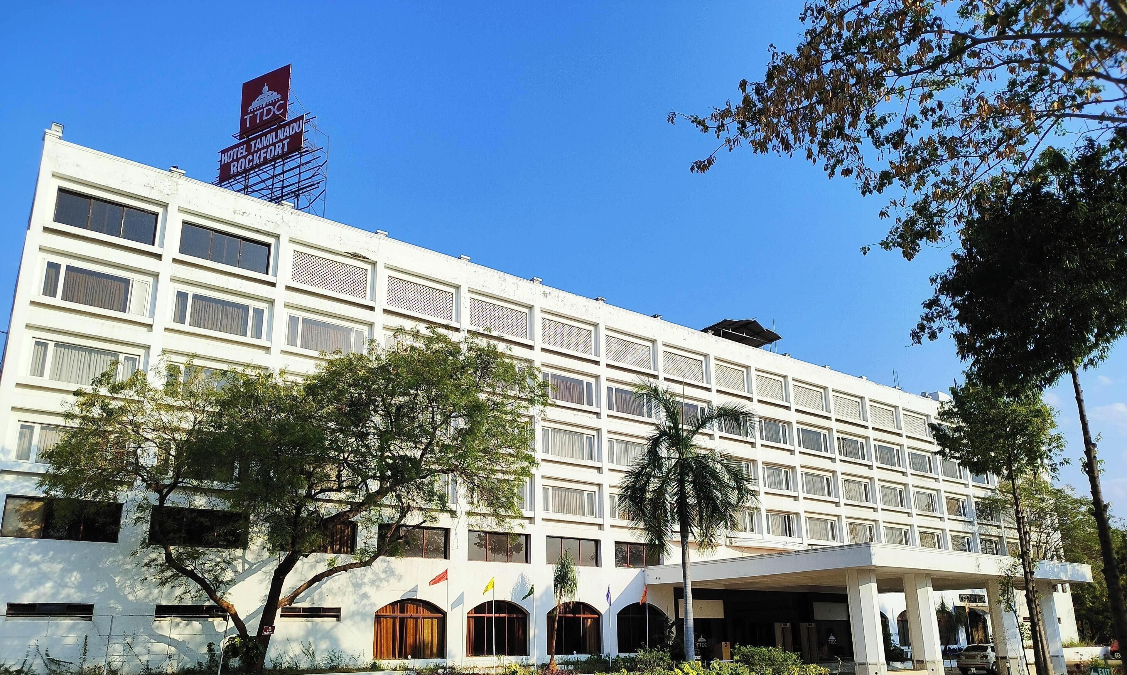 A multi-story hotel with a prominent sign, large windows, and a covered entrance area.