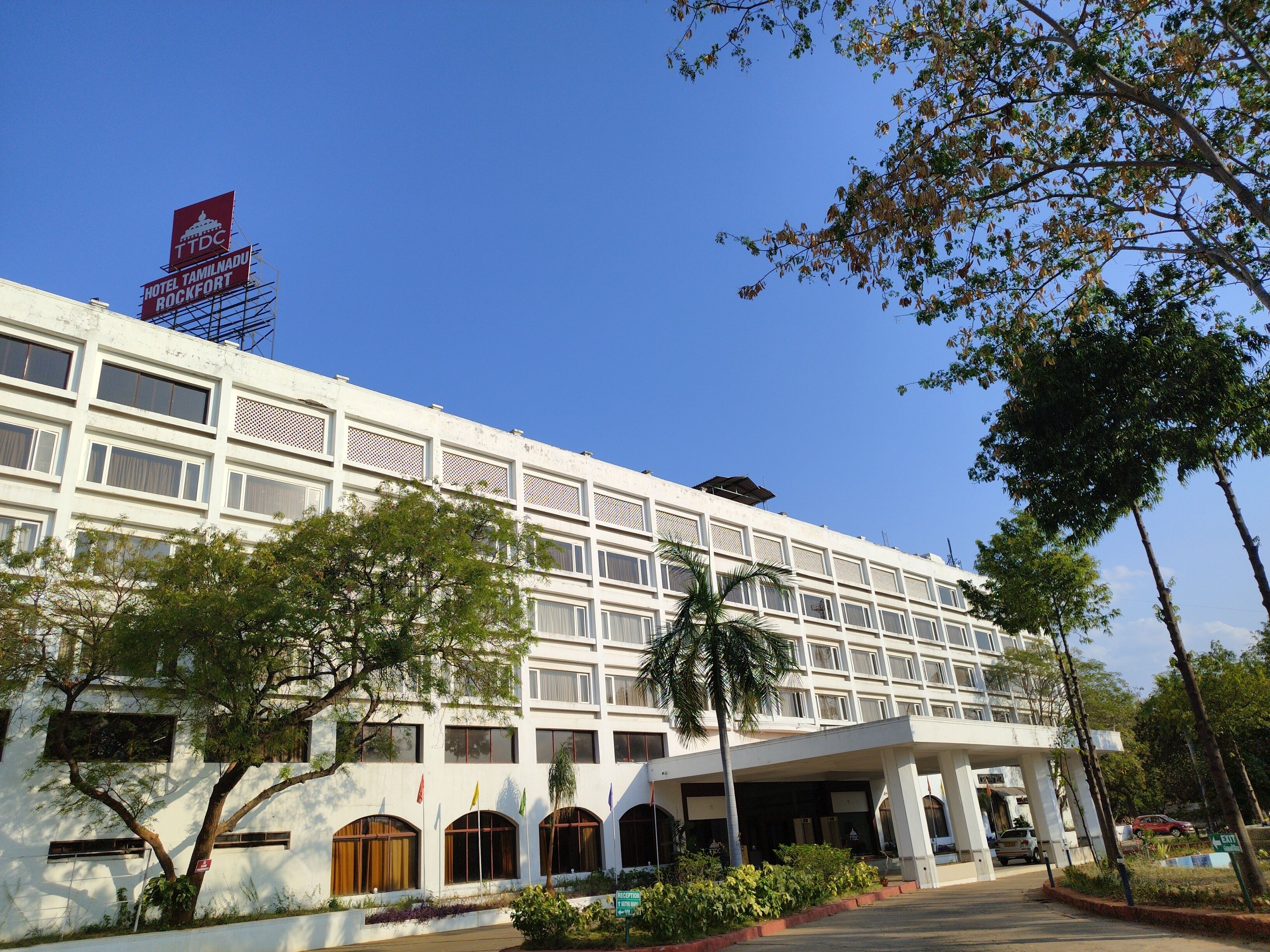 A multi-story hotel with a white facade, multiple windows, and a covered entrance area.