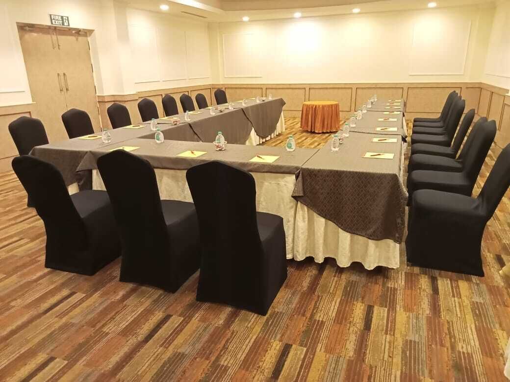 Un salón de conferencias con una larga mesa, sillas negras y una pequeña mesa redonda.