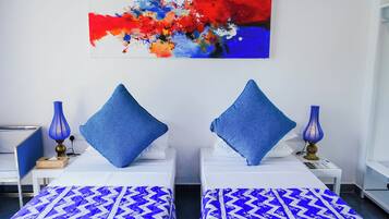Une chambre d’hôtel avec deux lits, chacun agrémenté d’un oreiller bleu et d’une couvre-lit à motifs.
