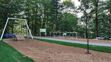 Ein Spielplatz mit Schaukeln, Bänken und einem befestigten Weg.