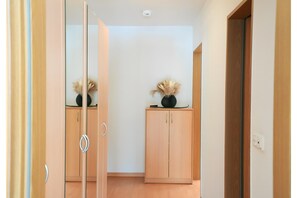 Ein Flur mit einem raumhohen Spiegel, einer Holzkassette mit einer Vase und einer Tür zu einem weiteren Zimmer.