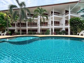 A hotel with a swimming pool, multiple balconies, and tropical plants. - Blue Neptuna Hotel Patong (Patong)