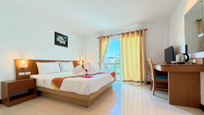Ein Hotelzimmer mit Bett, Nachttischen, einem Schreibtisch mit Stuhl, einem Fernseher und einem Fenster mit Vorhängen.