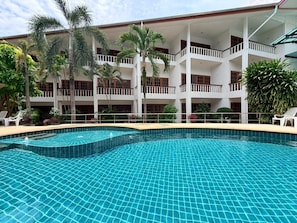 A hotel with a swimming pool, multiple balconies, and tropical plants. - Blue Neptuna Hotel Patong (Patong)