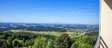 Une vue panoramique d’une vallée parsemée de maisons, sous un ciel bleu et dégagé.