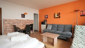 A modern hotel room with a bed, a sofa, a dining table, and a kitchenette. - Studio Rainer mit Pool und Sauna (Freyung)