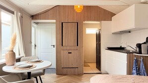 Eine kompakte Küche mit modernem Design, ein Essbereich mit rundem Tisch und eine sichtbare Tür zu einem anderen Raum.