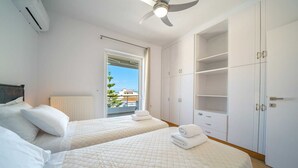 Quarto com duas camas, ventoinha no teto, radiador e um guarda-roupa grande.