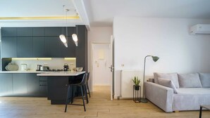 Uma cozinha moderna com uma ilha central, área de refeições com cadeiras, um sofá e um radiador.
