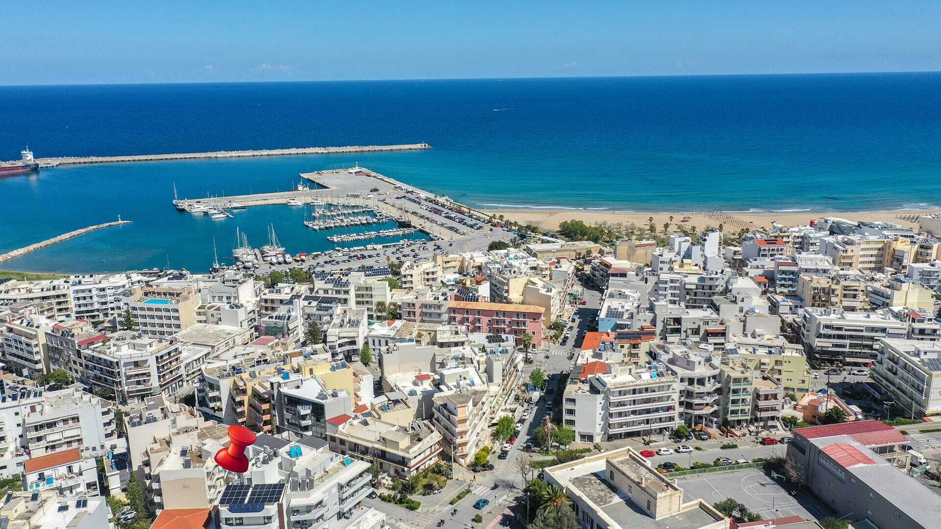 Een kuststadsgezicht met een jachthaven, gebouwen en een strand.