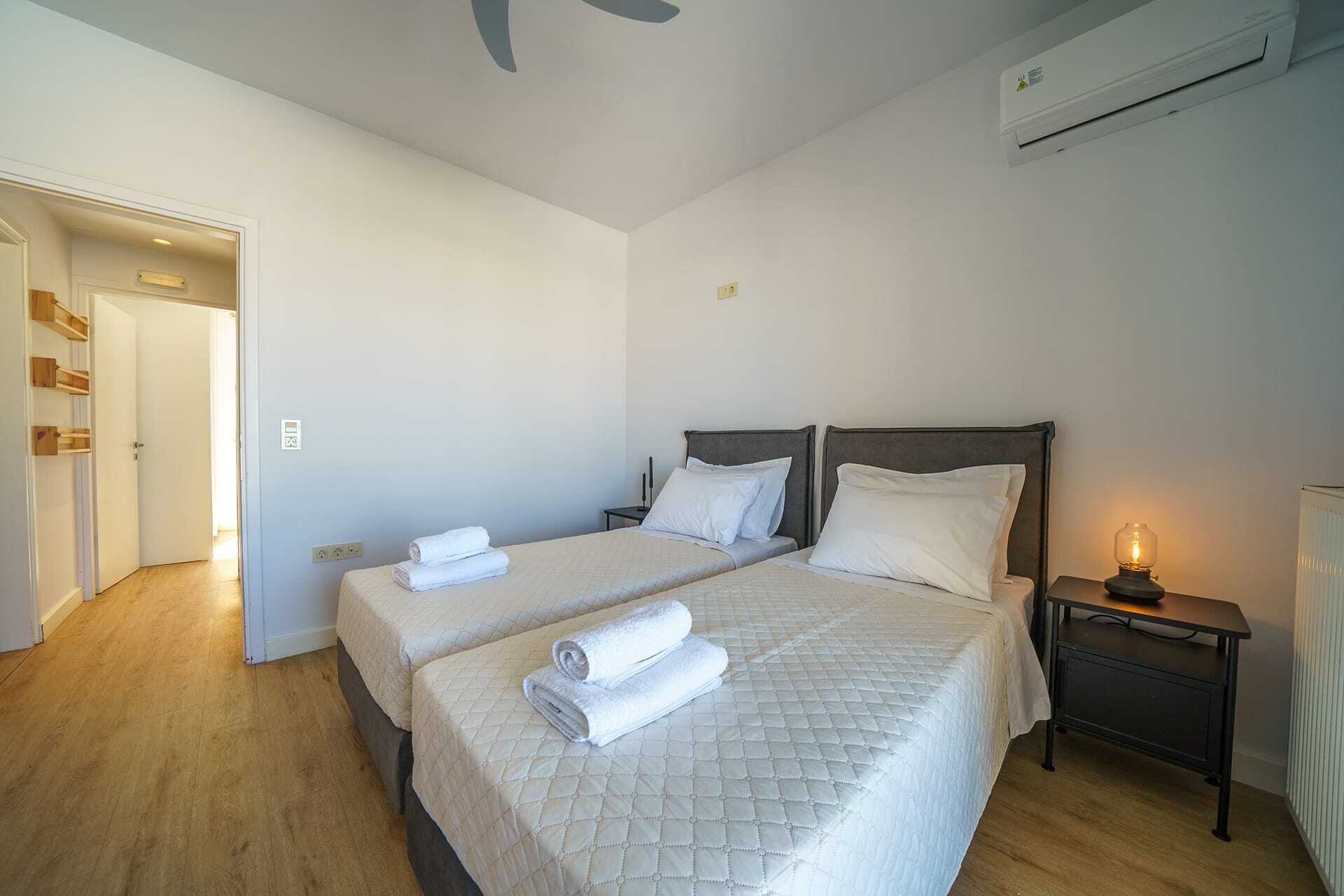 Una cama doble con cubrecama acolchado, una mesita de noche con lámpara y un equipo de aire acondicionado en la pared.