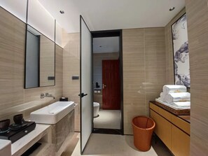A modern bathroom with a large mirror, a white sink, a toilet, and a wooden vanity with towels.