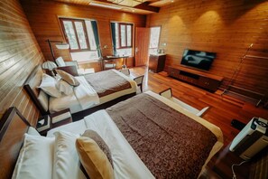 A room with two beds, a TV, a desk with a chair, and a window.