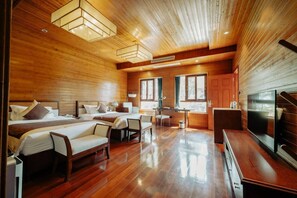 A wooden interior with two beds, a TV, and a small kitchenette.