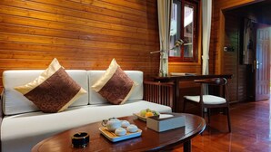 Une pièce aux murs lambrés, avec un canapé, une table sur laquelle est disposé un service à thé et une chaise.